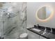 Modern bathroom with walk-in shower, glass doors, and marble-look accent wall at 2312 Herring Sw Rd, Atlanta, GA 30311