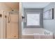 Bathroom featuring a glass-enclosed shower and soaking tub by a bright window at 4092 Duran Ln, Auburn, GA 30011