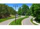 Scenic view of the community entrance with winding road, mature trees, and well-maintained landscaping at 782 Brooke View Drive, Canton, GA 30115
