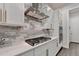 Modern kitchen features a gas cooktop, stainless steel range hood, white cabinetry and gray backsplash at 1045 Penny Ln, Roswell, GA 30076