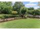 Lush landscaped backyard featuring manicured shrubs, retaining walls, mature trees, and a well-maintained lawn at 2737 Fontainebleau Drive, Dunwoody, GA 30360