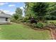 Lush landscaped backyard featuring manicured shrubs, retaining walls, mature trees, and a well-maintained lawn at 2737 Fontainebleau Drive, Dunwoody, GA 30360