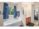 Bright bathroom showcases a tub-shower combo, vanity with cabinet, and window with blue curtains at 45 Ratliff Dr, Covington, GA 30016