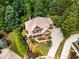 Stunning aerial view of a meticulously landscaped home surrounded by lush greenery and a winding driveway at 908 Basingstoke Ct, Suwanee, GA 30024