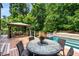 An outdoor living space with a dining table and a lounge area on a wooden deck with pool views at 908 Basingstoke Ct, Suwanee, GA 30024