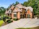 Stately brick home with well-manicured landscaping, attached garages, and a circular driveway at 908 Basingstoke Ct, Suwanee, GA 30024