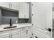 Well-lit laundry room features white cabinets, quartz countertops, and modern black faucet and hardware at 908 Basingstoke Ct, Suwanee, GA 30024