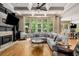 Bright living room features hardwood floors, fireplace, ceiling fan and a wall of windows overlooking trees at 908 Basingstoke Ct, Suwanee, GA 30024