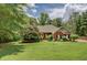 Beautiful brick home featuring a lush green lawn, mature trees, and lovely landscaping at 1041 Flat Rock Rd, Covington, GA 30014