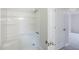 Bright bathroom featuring a shower-tub combo with white tile surround and neutral wall paint at 49 Sweetwater Ct, Powder Springs, GA 30127