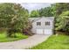 Charming home featuring a two-car garage, inviting staircase, and blossoming tree in a lush, green lawn at 49 Sweetwater Ct, Powder Springs, GA 30127