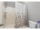 Bathroom featuring a walk-in shower with a floral shower curtain and standard toilet at 1612 Branch Creek Cv, Lawrenceville, GA 30043