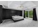 Spacious main bedroom with tray ceiling, a modern ceiling fan, large window, and black accent wall at 1612 Branch Creek Cv, Lawrenceville, GA 30043