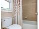 Bathroom with beige shower tile, leaf-patterned shower curtain, toilet, and a window with natural lighting at 2850 Seagrave Way, Marietta, GA 30066