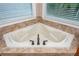 Bright soaking tub featuring a jetted tub, bronze fixtures, and tile surround at 2850 Seagrave Way, Marietta, GA 30066