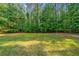 A sprawling backyard surrounded by lush green trees in a wooded area at 390 Glengarry Chase, Covington, GA 30014