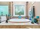 Bathroom featuring a soaking tub with tile surround, decorative window, and luxurious fixtures at 390 Glengarry Chase, Covington, GA 30014