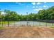 Fenced community tennis court with lighting and benches is surrounded by mature trees at 390 Glengarry Chase, Covington, GA 30014