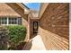 Close-up of the brick home's front entrance with an oval-windowed door and manicured shrubbery at 1553 Queen Elizabeth Dr, Locust Grove, GA 30248