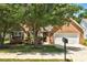 Charming brick home featuring a well-maintained front yard, mature tree, and a two-car garage at 1553 Queen Elizabeth Dr, Locust Grove, GA 30248