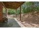 Back patio with a concrete floor under a wooden deck featuring brick wall and lush greenery at 5060 Windcrest Lane, Alpharetta, GA 30022