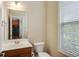 Cozy half-bathroom featuring a vanity sink, toilet, and natural lighting at 5060 Windcrest Lane, Alpharetta, GA 30022