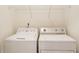 A compact laundry area equipped with a side-by-side washer and dryer and wire shelf for storage at 5060 Windcrest Lane, Alpharetta, GA 30022