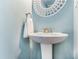 Close up of pedestal sink in powder blue bathroom with circle accent mirror and brushed nickel fixtures at 6940 Roswell Road Rd # 16B, Atlanta, GA 30328