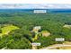 Aerial view of a home surrounded by dense trees, driveways, and a large field at 705 S Bethany Rd, Mcdonough, GA 30252