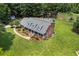 Aerial view of a brick home featuring a covered front porch and dormer windows, set on a sprawling green lawn at 705 S Bethany Rd, Mcdonough, GA 30252