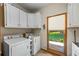Bright laundry room with modern washer and dryer, white cabinets, and view to the backyard at 705 S Bethany Rd, Mcdonough, GA 30252