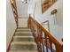 Carpeted staircase featuring a wooden banister and natural light coming from the window at the top of the stairs at 705 S Bethany Rd, Mcdonough, GA 30252