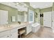 Well lit bathroom with soaking tub, dual sinks, stool and tile flooring at 1065 Bookhout Drive Dr, Cumming, GA 30041