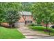 Brick home featuring a well-manicured lawn and two-car garage, surrounded by mature trees at 1065 Bookhout Drive Dr, Cumming, GA 30041