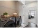 A well-lit laundry room featuring modern washer and dryer units with a wire shelf for storage at 621 Hanlon Way, Alpharetta, GA 30009