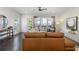 Bright living room with dark wood floors, large brown leather sofa, and ample natural light at 621 Hanlon Way, Alpharetta, GA 30009
