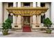 Grand building entrance with gold awning, columns, red carpet, and potted trees at 75 Ponce De Leon Ne Ave # 1006, Atlanta, GA 30308