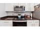 Bright kitchen featuring granite countertops, stainless steel appliances, and white cabinetry with gold hardware at 3040 Peachtree Rd, Atlanta, GA 30305