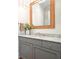 Bathroom vanity with gray cabinetry, light countertops, and a rattan-framed mirror at 6930 Wesley Hughes Rd, Cumming, GA 30040