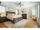 Main bedroom with a dark wood bed frame, modern ceiling fan, and hardwood floors at 6930 Wesley Hughes Rd, Cumming, GA 30040