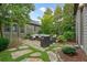 Outdoor stone patio area with wicker seating, surrounded by trees and manicured shrubs at 6930 Wesley Hughes Rd, Cumming, GA 30040