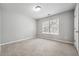 A carpeted bedroom featuring a window offering natural light and neutral colored walls at 5590 Bright Cross Way, Suwanee, GA 30024