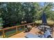 Back deck featuring wooden railings, a table with chairs, and green foliage at 3675 Ridgeway Ter, Suwanee, GA 30024
