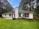 Back of house with black roof, white siding, chimney, a patio, and a well-maintained green lawn at 46 Timber Walk Dr, Sharpsburg, GA 30277