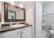Bathroom featuring a framed mirror, white vanity, tiled floor and a toilet with shelves at 1810 Ashborough Se Rd # G, Marietta, GA 30067