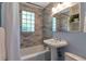 Bathroom featuring tub with gray tile surround, glass block window, and pedestal sink at 2002 Shalimar Ne Dr, Chamblee, GA 30345