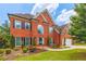Charming two-story red brick home featuring black shutters, a well-manicured lawn, and a two-car garage at 1219 Hadaway Ct, Lawrenceville, GA 30043