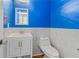 Stylish half bath featuring a modern vanity and toilet, complemented by vibrant blue walls at 1219 Hadaway Ct, Lawrenceville, GA 30043