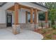 Inviting front porch with stylish lighting, brick accents, and wood columns for a cozy entryway at 153 Alaina Rd, Holly Springs, GA 30115