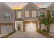 Townhome exterior featuring a two-car garage and brick accents, set against a colorful sunset at 1958 Dillon Dr, Lithonia, GA 30058